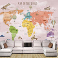 Papier peint carte du monde rose avec animaux, avions et montgolfières au-dessus d'un canapé