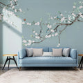 Panoramique bleu avec branches de magnolia en fleurs, oiseaux et papillons derrière un canapé