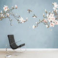 Branches de magnolia fleuries et deux oiseaux sur fond bleu gris, fauteuil noir