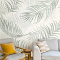 Mur de salon orné de grandes feuilles de palmier vert sauge sur fond crème