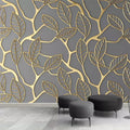 Papier peint panoramique feuilles dorées sur fond gris avec poufs noirs ronds