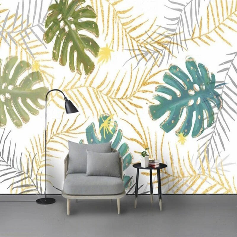 Mur orné de feuilles de monstera vertes et de palmes dorées derrière un fauteuil gris