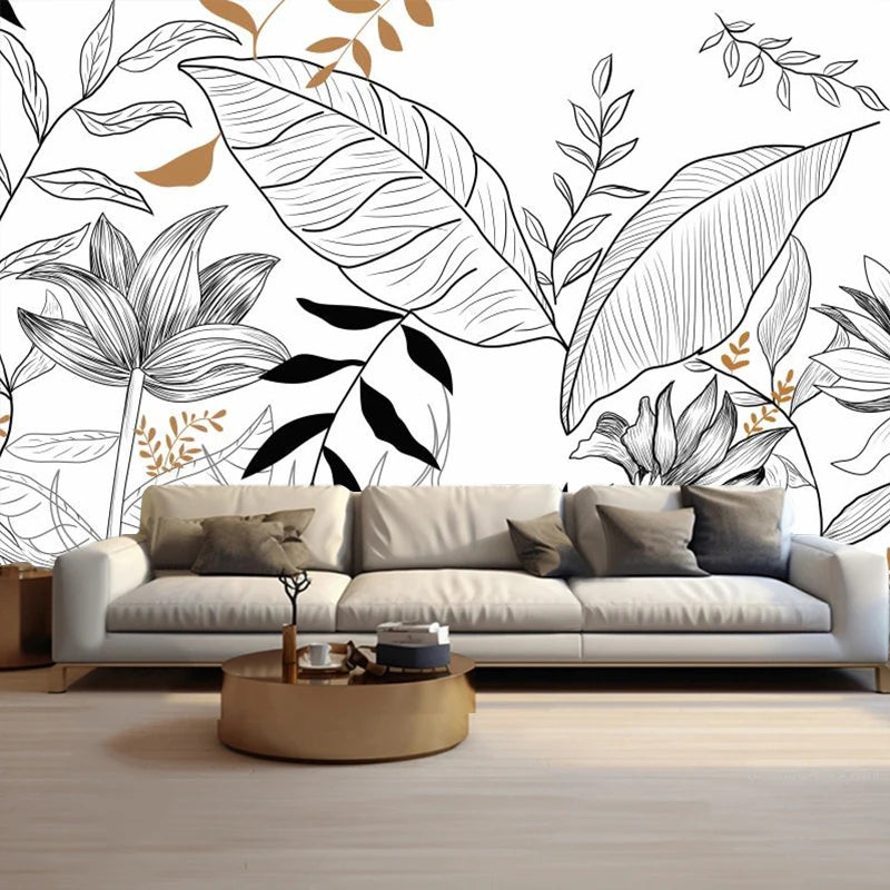 Papier peint feuillage tropical au trait noir et blanc derrière un canapé beige