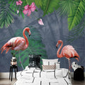 Papier peint panoramique tropical avec deux flamants roses et feuillage vert derrière un lit