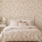 Papier peint fleuri rose et beige derrière un lit en métal blanc