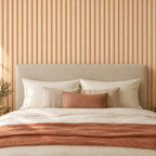 Chambre avec papier peint à fines rayures terracotta sur fond beige derrière le lit