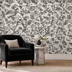 Mur de salon couvert d'un motif fleuri noir et blanc, fauteuil sombre et guéridon en marbre